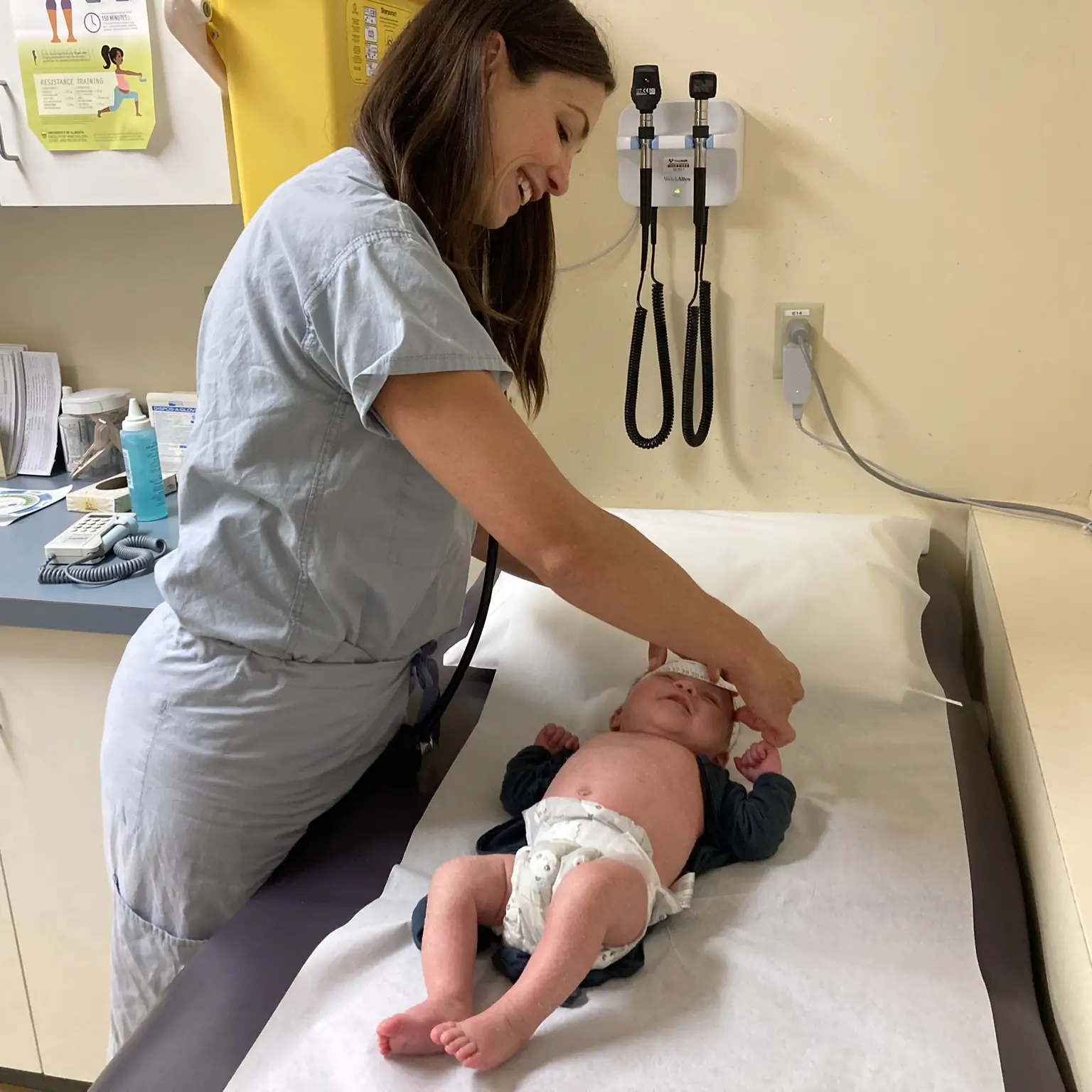 Dr Stephanie Balog measuring the head of a newborn on an examination table.