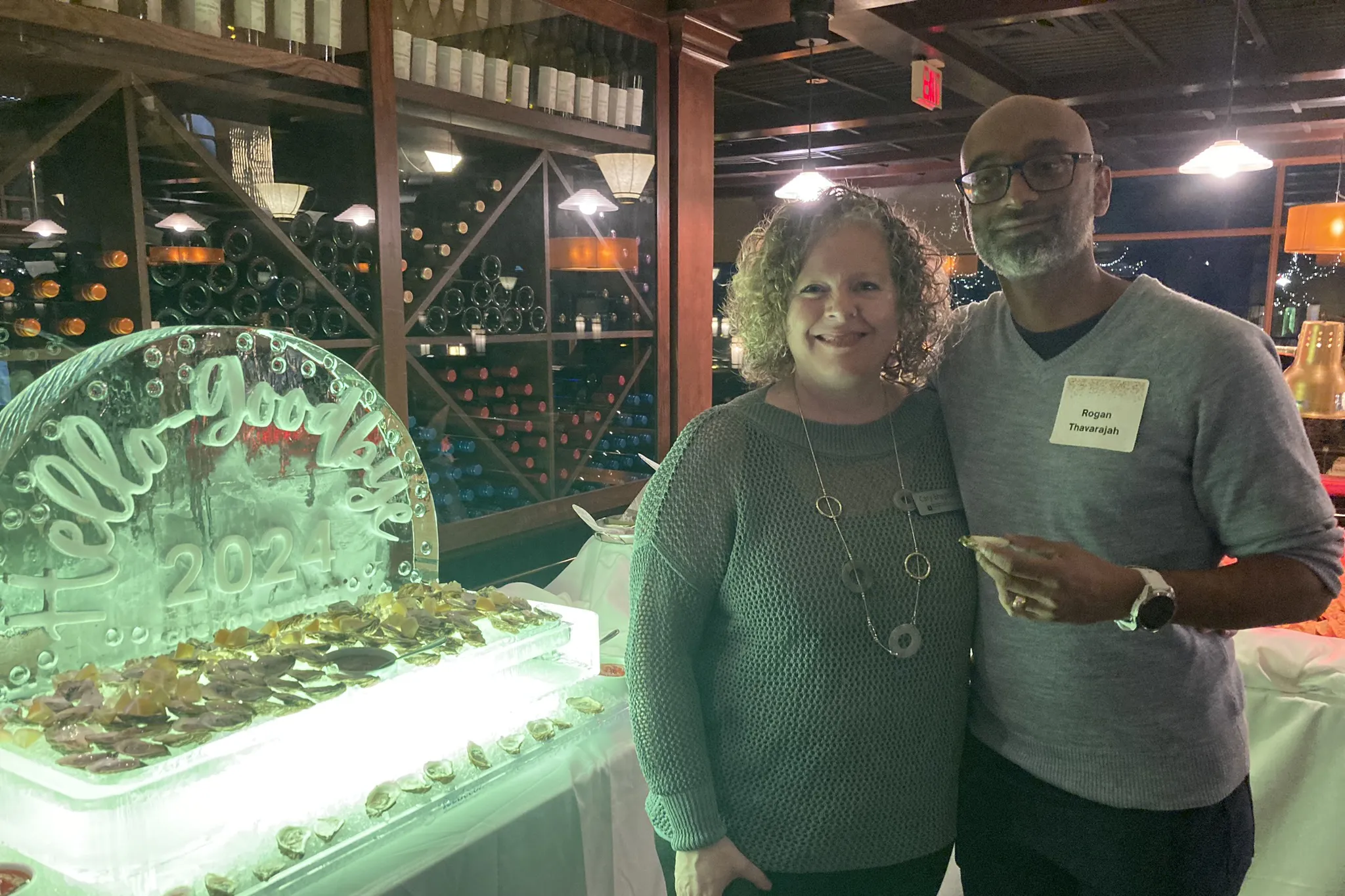 Two colleagues standing in front of an ice sculpture at the 'Hello Goodbye' event in 2024, South Surrey White Rock.