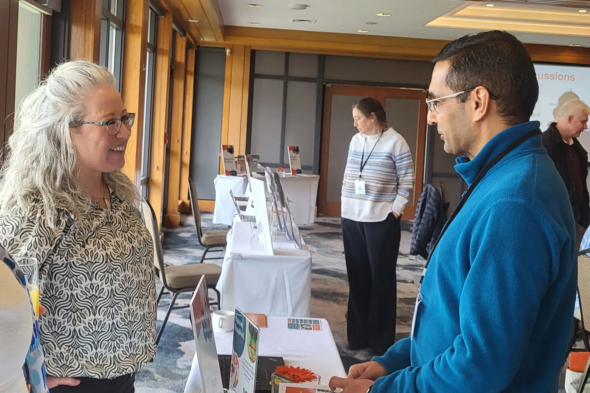 Team member discussing healthcare information with an attendee at an information booth during a healthcare event in South Surrey White Rock.