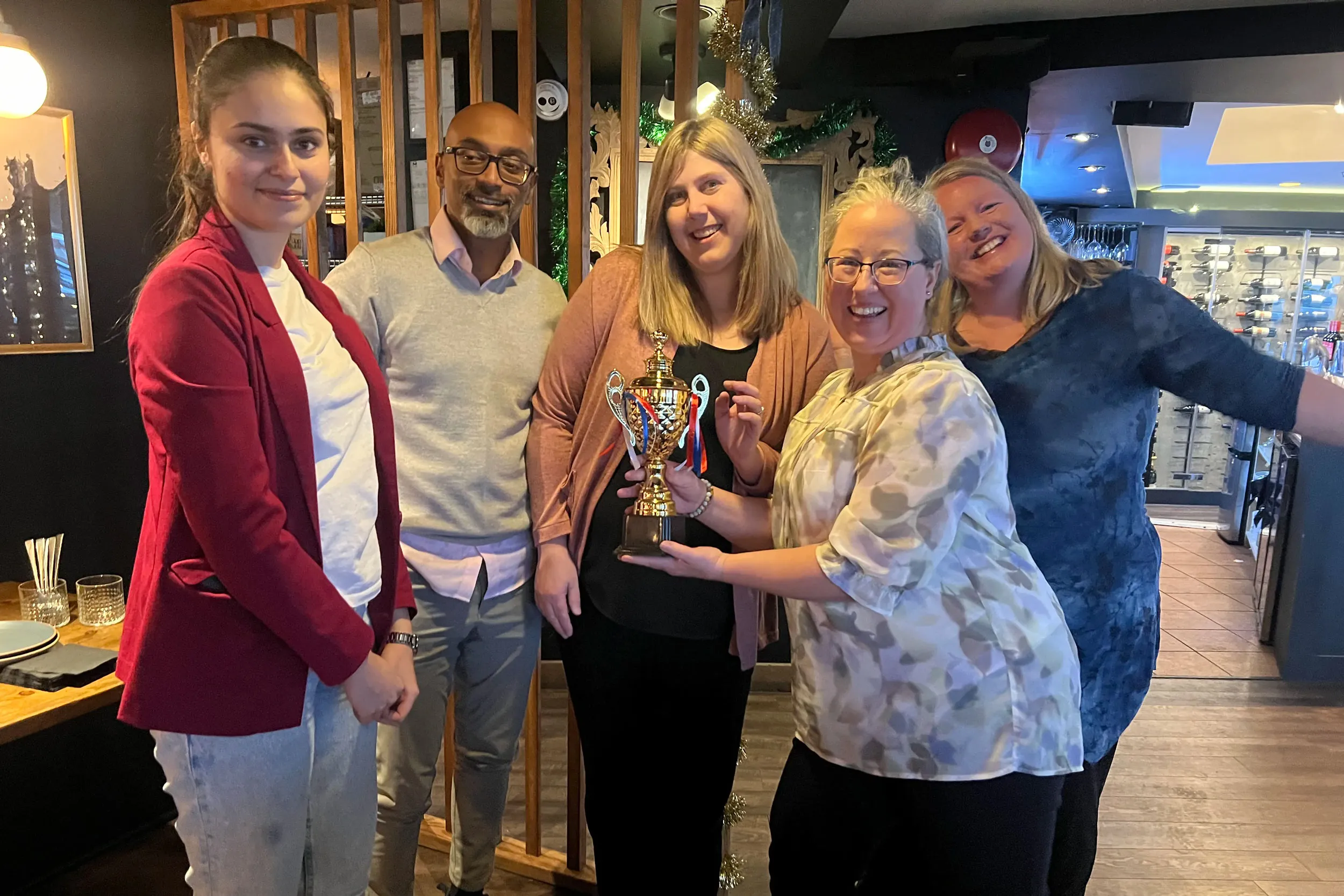 Group of colleagues posing with a trophy during an award ceremony at a team event in South Surrey White Rock.