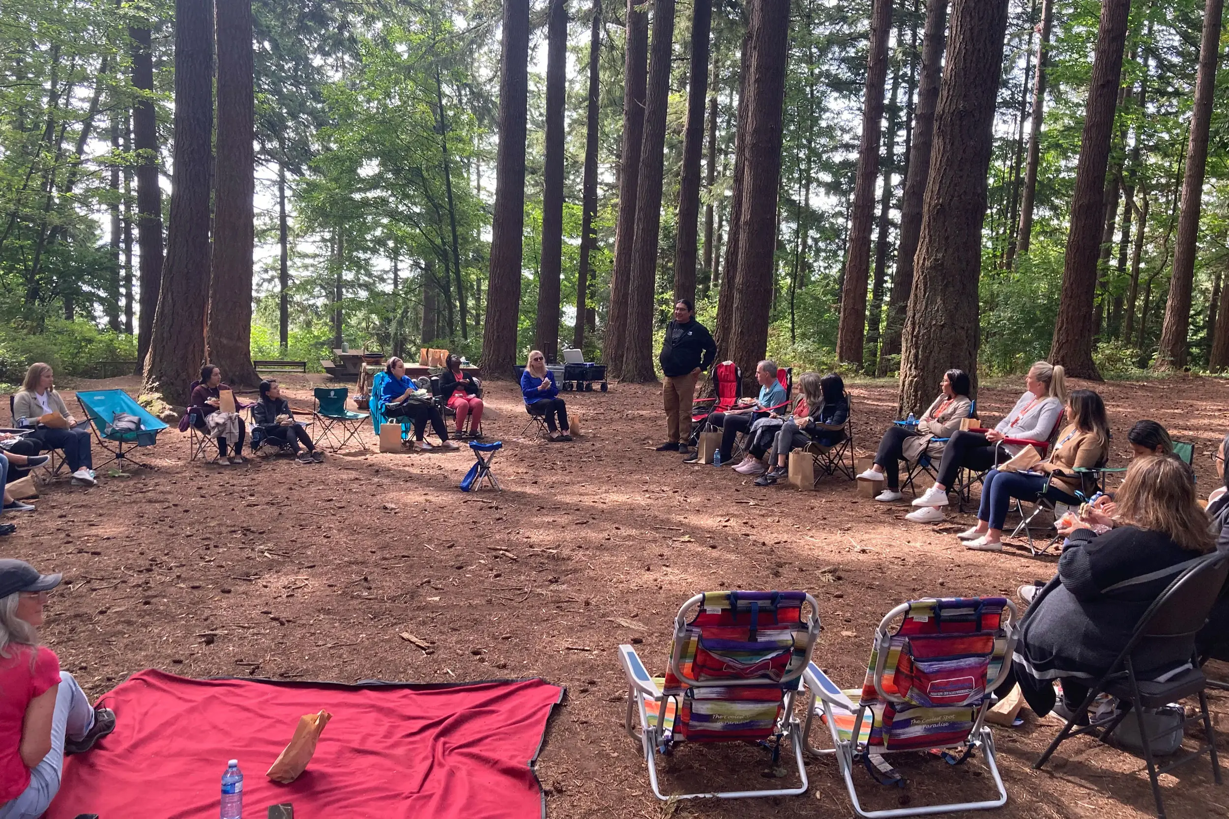 Group of individuals seated in a circle in a forest setting during a team-building retreat in South Surrey White Rock.