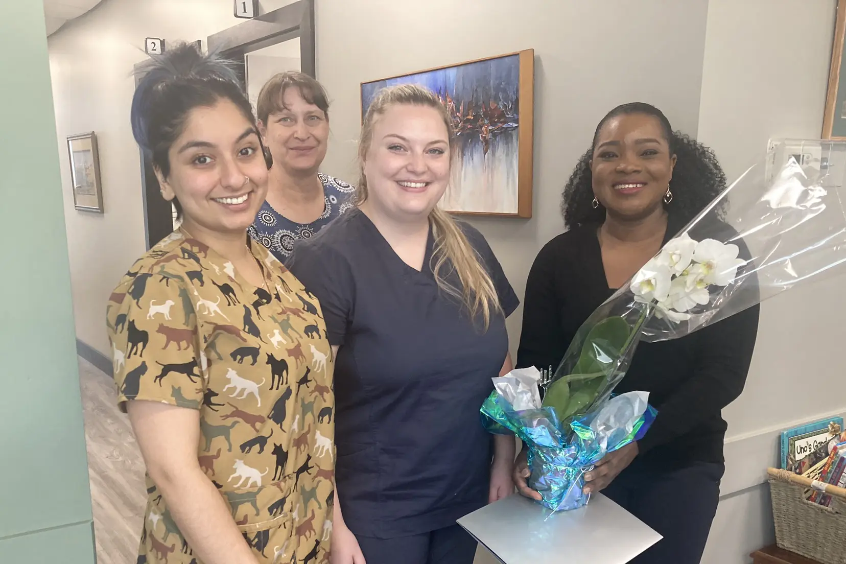 Group of medical staff celebrating in a clinic in White Rock, South Surrey, with one holding a potted orchid.